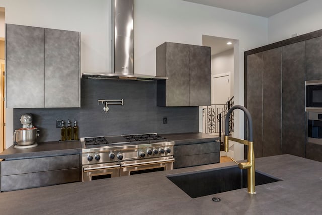 kitchen featuring sink, stainless steel appliances, backsplash, and wall chimney range hood