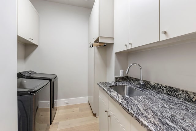 washroom featuring washer and dryer, sink, cabinets, and light hardwood / wood-style flooring