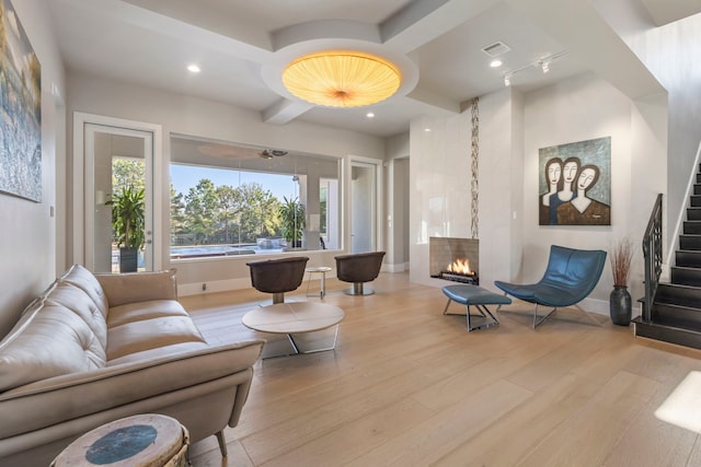 living room featuring a fireplace, beam ceiling, and light wood-type flooring