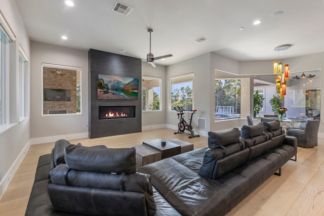 living room with a fireplace, ceiling fan, and light hardwood / wood-style flooring