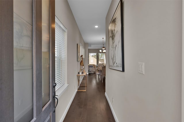 hallway with dark hardwood / wood-style flooring and a notable chandelier