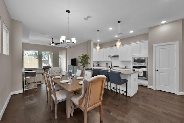 dining area with dark hardwood / wood-style floors and ceiling fan with notable chandelier