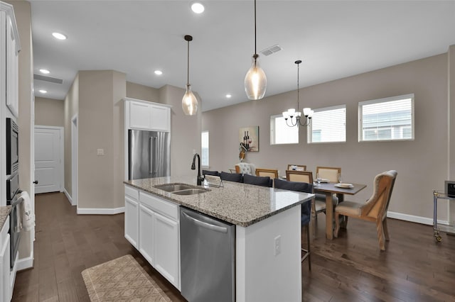 kitchen with appliances with stainless steel finishes, dark hardwood / wood-style flooring, light stone counters, a kitchen island with sink, and white cabinets