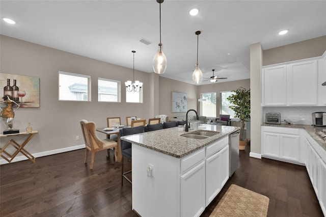 kitchen with white cabinetry, sink, light stone counters, an island with sink, and pendant lighting