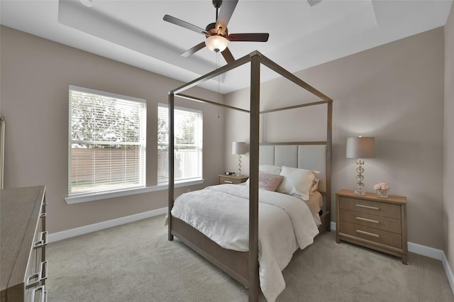 bedroom with a tray ceiling, ceiling fan, and light colored carpet