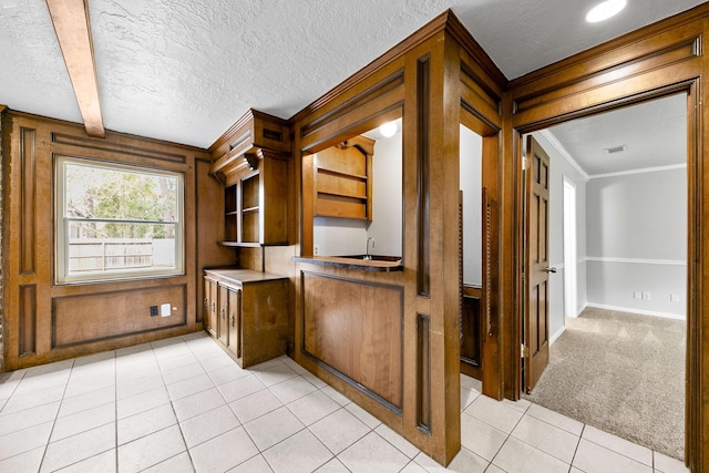 unfurnished office with wood walls, a textured ceiling, crown molding, and light tile patterned flooring