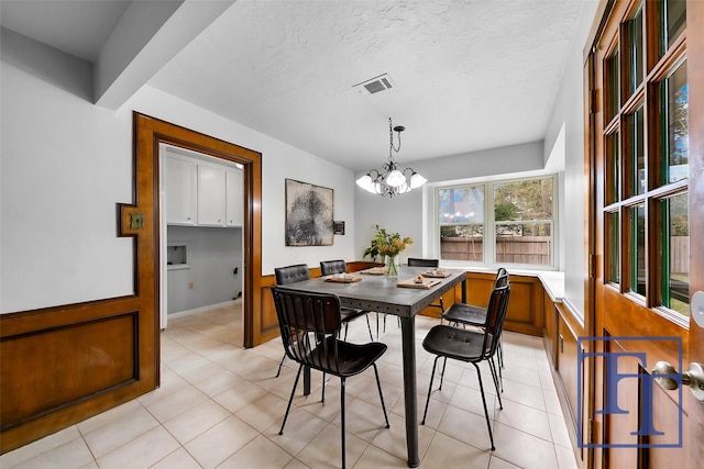 tiled dining area with a textured ceiling and a chandelier