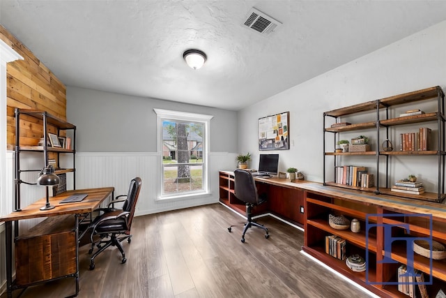 home office featuring wood walls, wood-type flooring, and a textured ceiling