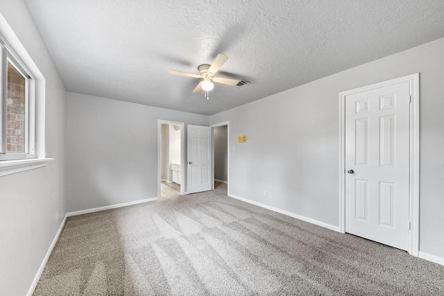 unfurnished bedroom with ceiling fan, ensuite bathroom, light carpet, and a textured ceiling