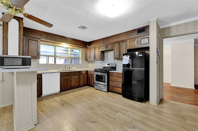 kitchen featuring sink, decorative backsplash, ornamental molding, light hardwood / wood-style floors, and stainless steel appliances