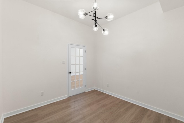 empty room with hardwood / wood-style floors and a chandelier