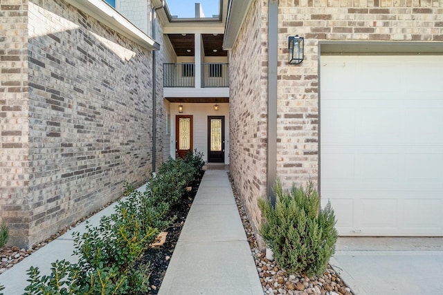 view of exterior entry with a balcony and a garage