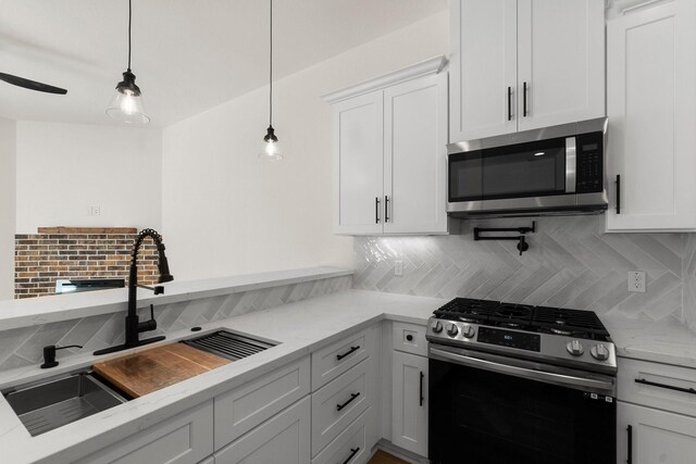 kitchen with white cabinets, hanging light fixtures, appliances with stainless steel finishes, and tasteful backsplash