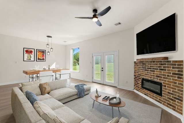 living room with hardwood / wood-style floors, french doors, a brick fireplace, and ceiling fan