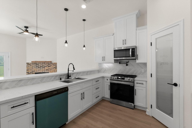 kitchen featuring pendant lighting, white cabinetry, sink, and appliances with stainless steel finishes