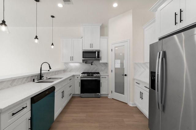 kitchen with pendant lighting, sink, white cabinets, and stainless steel appliances