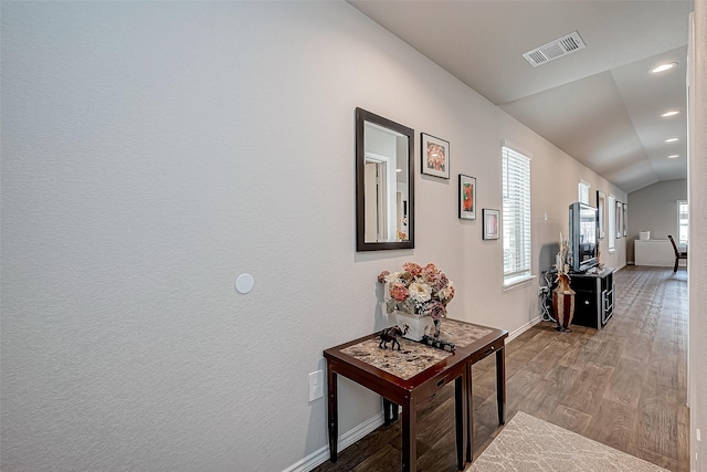 corridor with hardwood / wood-style flooring and lofted ceiling