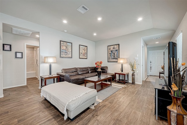 living room with light hardwood / wood-style floors and vaulted ceiling