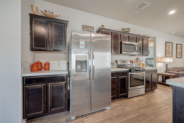 kitchen with dark brown cabinetry, light hardwood / wood-style flooring, and appliances with stainless steel finishes