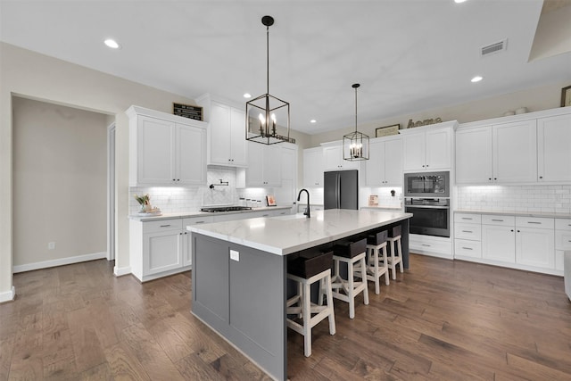 kitchen featuring stainless steel oven, a breakfast bar, built in microwave, white cabinets, and fridge