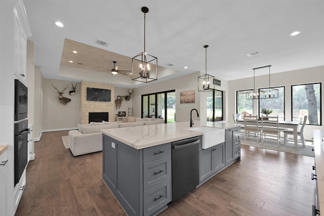 kitchen with black appliances, dark hardwood / wood-style flooring, a stone fireplace, and decorative light fixtures