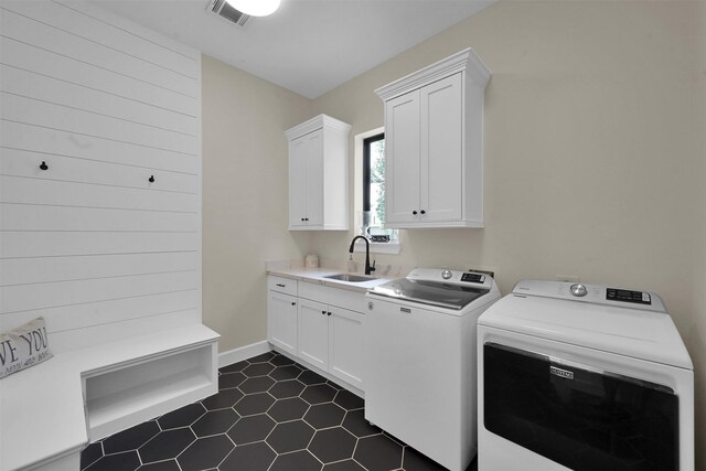 laundry room with dark tile patterned floors, cabinets, separate washer and dryer, and sink