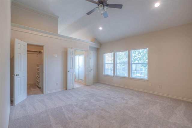 unfurnished bedroom featuring light carpet, a spacious closet, lofted ceiling, and ceiling fan