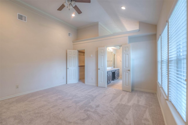 unfurnished bedroom with lofted ceiling, ensuite bath, a spacious closet, light carpet, and ornamental molding