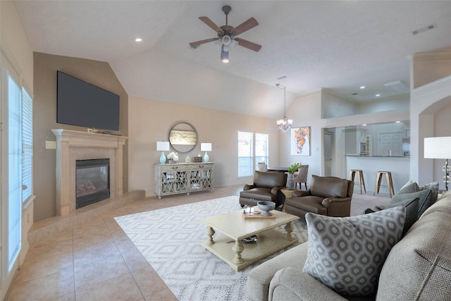 tiled living room featuring lofted ceiling, ceiling fan with notable chandelier, and a fireplace