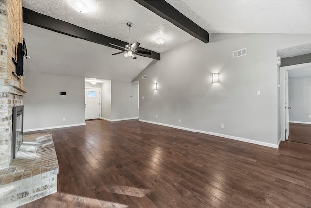 unfurnished living room with ceiling fan, dark wood-type flooring, a stone fireplace, vaulted ceiling with beams, and a textured ceiling