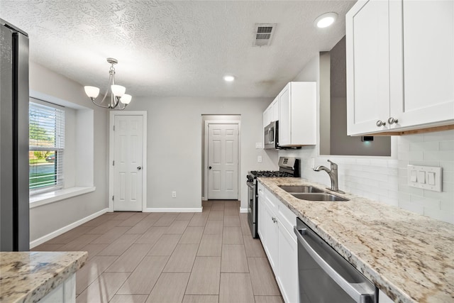 kitchen featuring white cabinets, sink, hanging light fixtures, light stone countertops, and appliances with stainless steel finishes