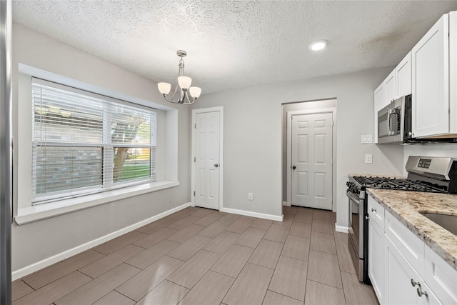 kitchen featuring decorative light fixtures, light stone countertops, white cabinetry, and stainless steel appliances