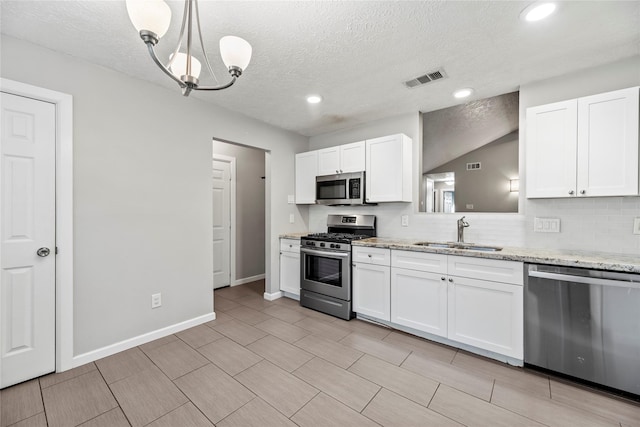 kitchen with pendant lighting, sink, a textured ceiling, white cabinetry, and stainless steel appliances