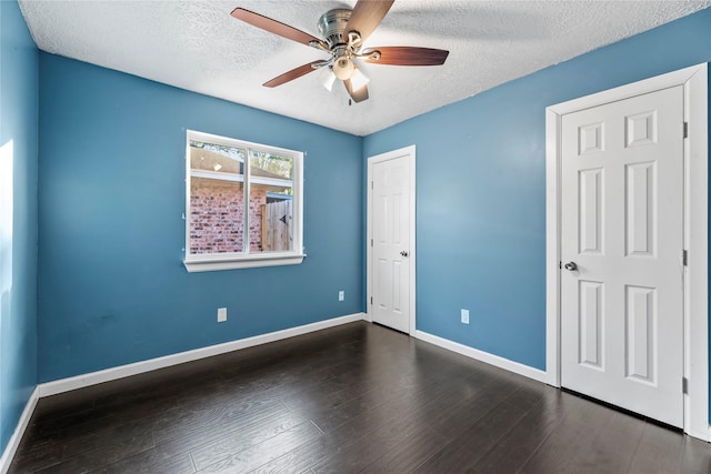 unfurnished bedroom with a textured ceiling, dark hardwood / wood-style floors, and ceiling fan