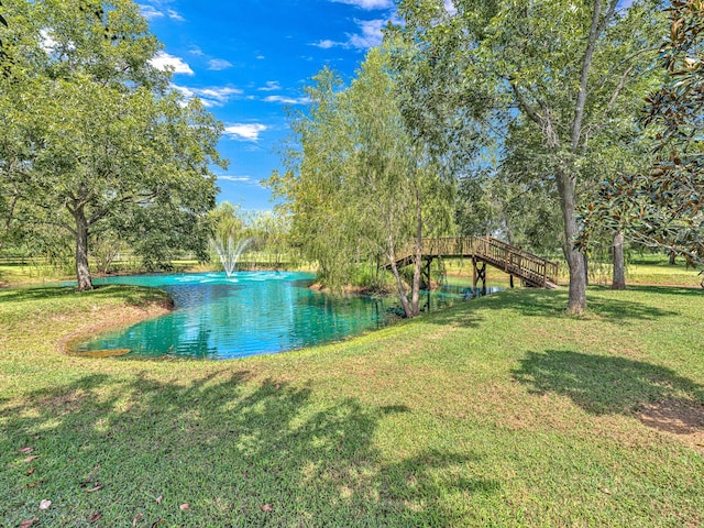 view of pool with a water view and a lawn