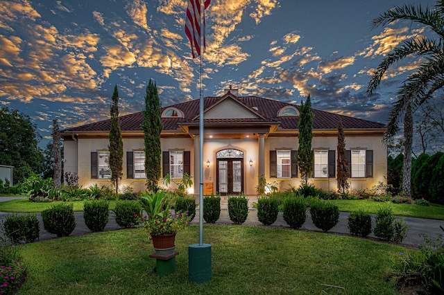 mediterranean / spanish-style home with a lawn and french doors