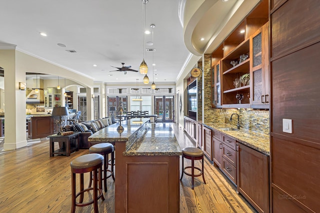 kitchen featuring pendant lighting, decorative backsplash, light wood-type flooring, and ornamental molding