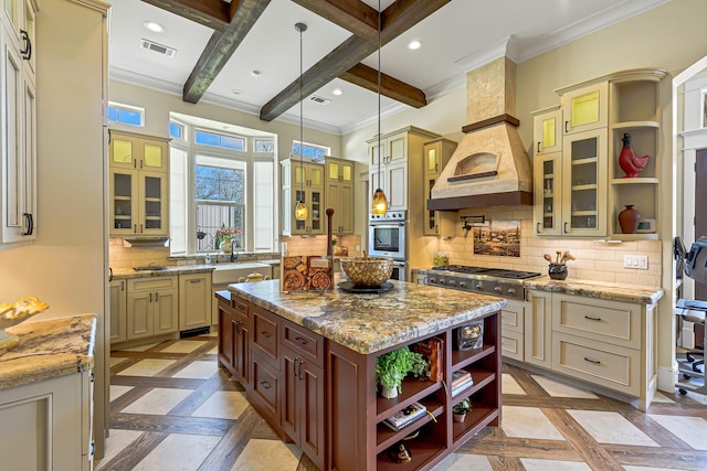 kitchen with beam ceiling, a center island, hanging light fixtures, cream cabinets, and decorative backsplash