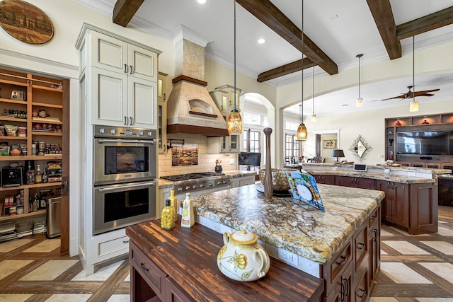 kitchen with dark stone counters, a kitchen island, stainless steel appliances, and decorative light fixtures