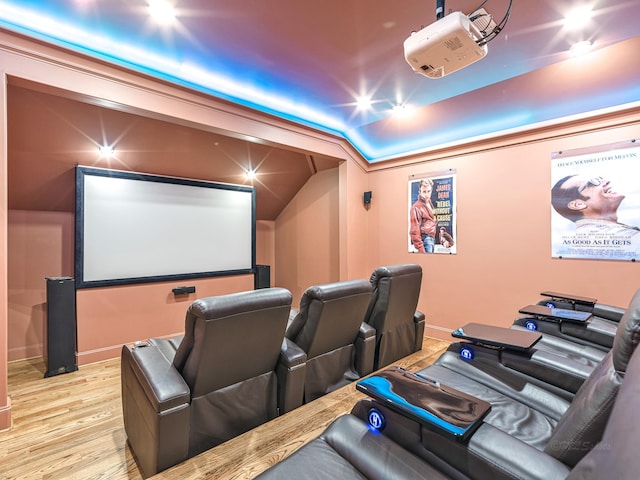 cinema room featuring light wood-type flooring and vaulted ceiling