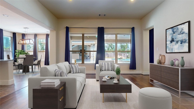 living room with wood-type flooring, an inviting chandelier, and a healthy amount of sunlight