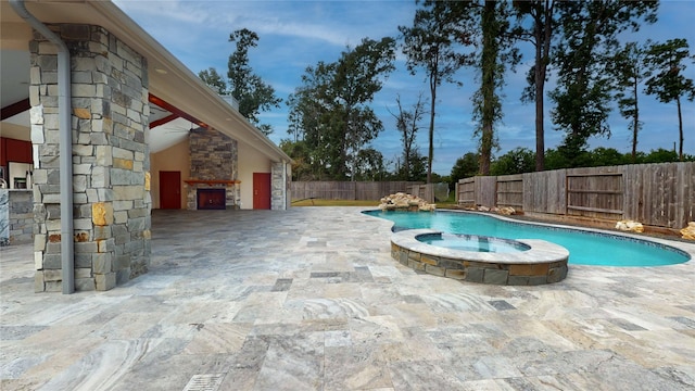 view of pool featuring an outdoor stone fireplace and a patio