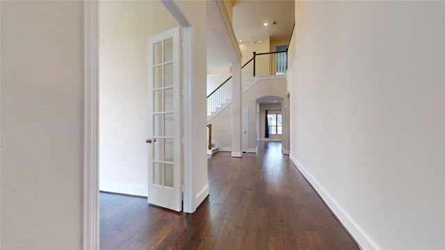 corridor with dark hardwood / wood-style flooring, a high ceiling, and french doors