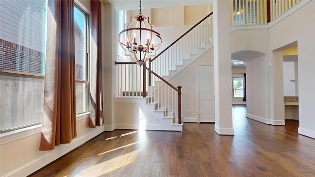 foyer with a towering ceiling, dark hardwood / wood-style floors, and an inviting chandelier