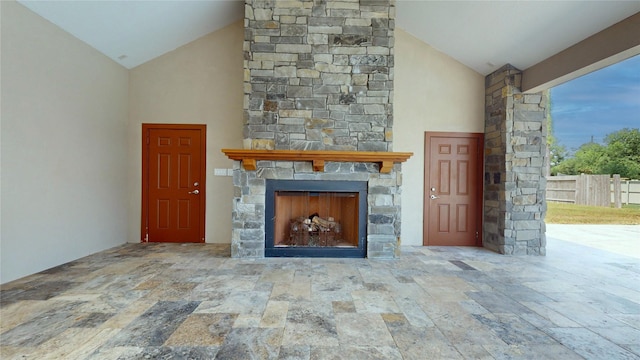 unfurnished living room with high vaulted ceiling and a stone fireplace