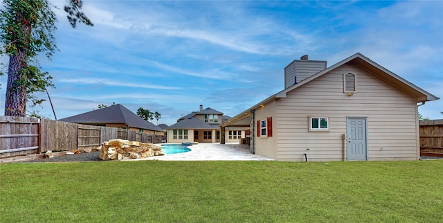 rear view of house featuring a yard, a fenced in pool, and a patio area