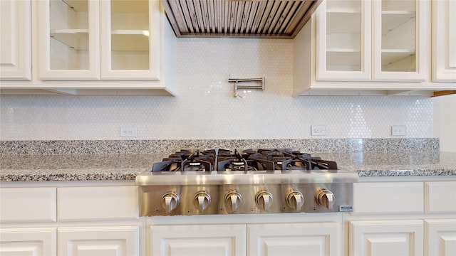 kitchen featuring decorative backsplash, light stone countertops, custom exhaust hood, white cabinets, and stainless steel gas stovetop