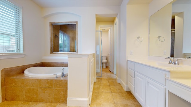 bathroom with vanity, tile patterned flooring, a relaxing tiled tub, and toilet