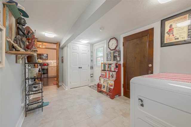 entryway featuring light tile patterned floors, a textured ceiling, and washer / clothes dryer