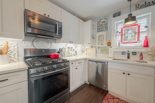 kitchen featuring white cabinetry, sink, dark hardwood / wood-style flooring, pendant lighting, and appliances with stainless steel finishes